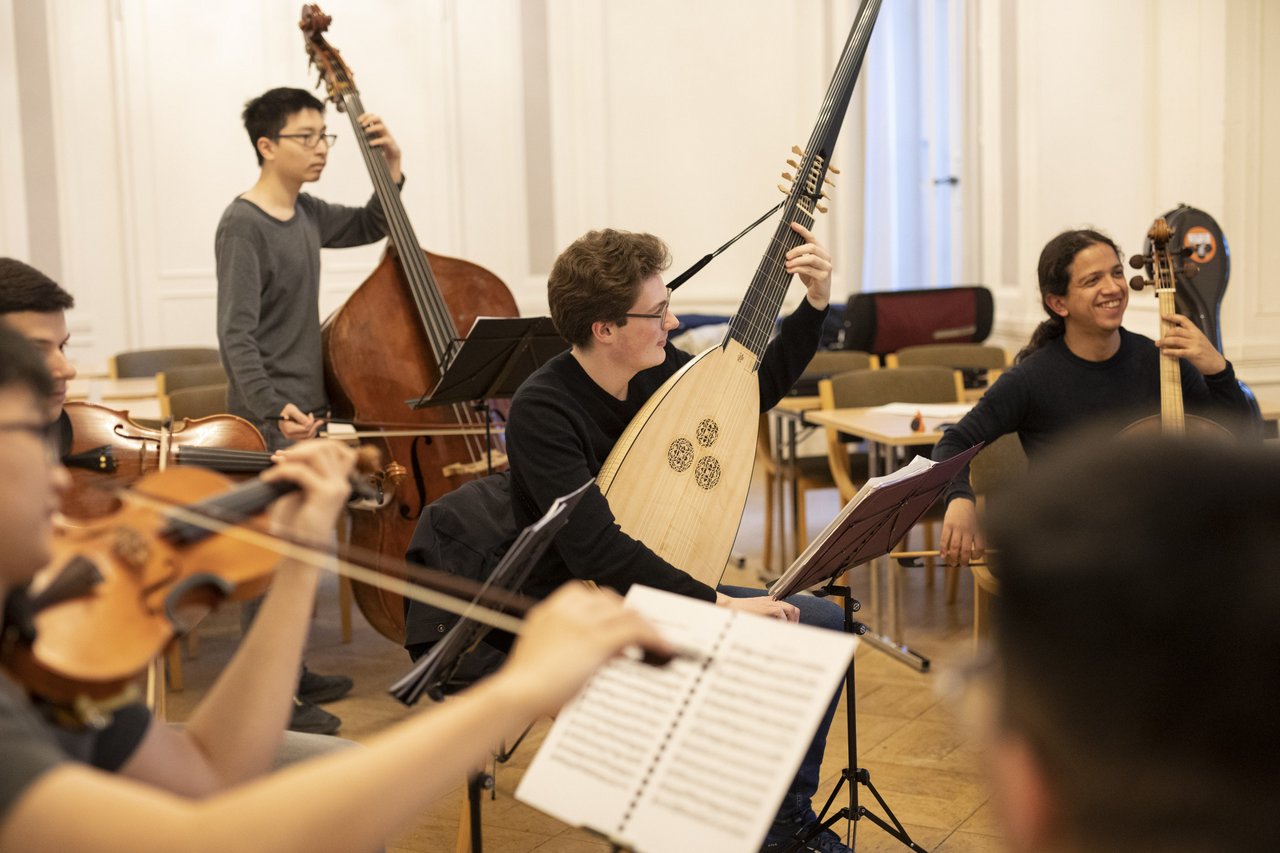 sechs Personen mit barocken Saiteninstrumenten und Notenständern