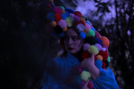 Person mit bunter Perücke aus Kugeln in der Dämmerung