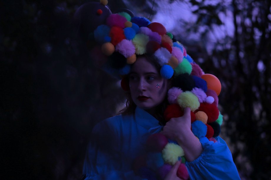 Person mit bunter Perücke aus Kugeln in der Dämmerung