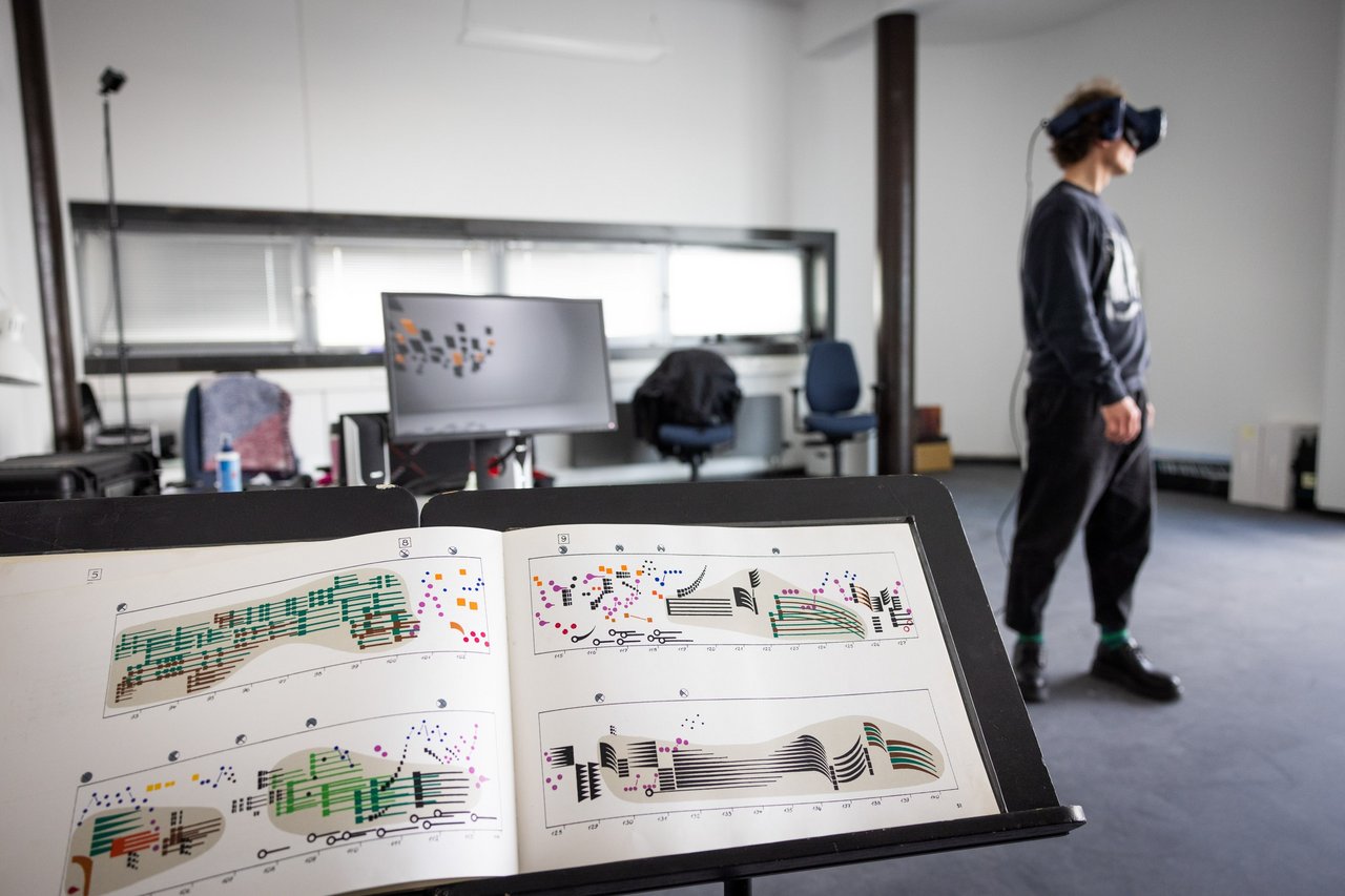 Notenständer im Vordergrund und Person mit 3D-Bille im Hintergrund