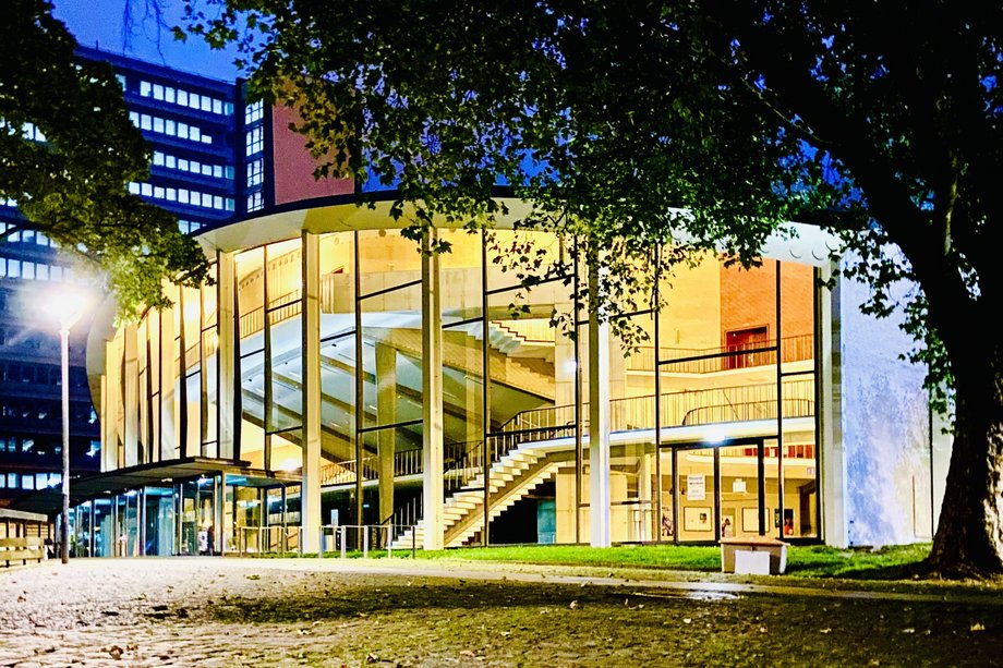 Ansicht eines Gebäudes mit Glasfassade am Abend im Schein einer Straßenlaterne