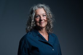 Foto einer lächelnden Frau mit langen, lockigen Haaren