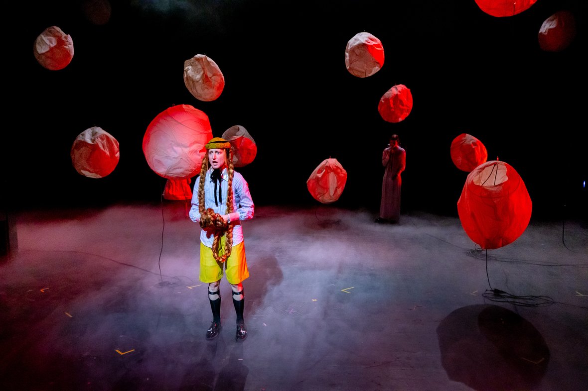 A person with floating red balls on the stage