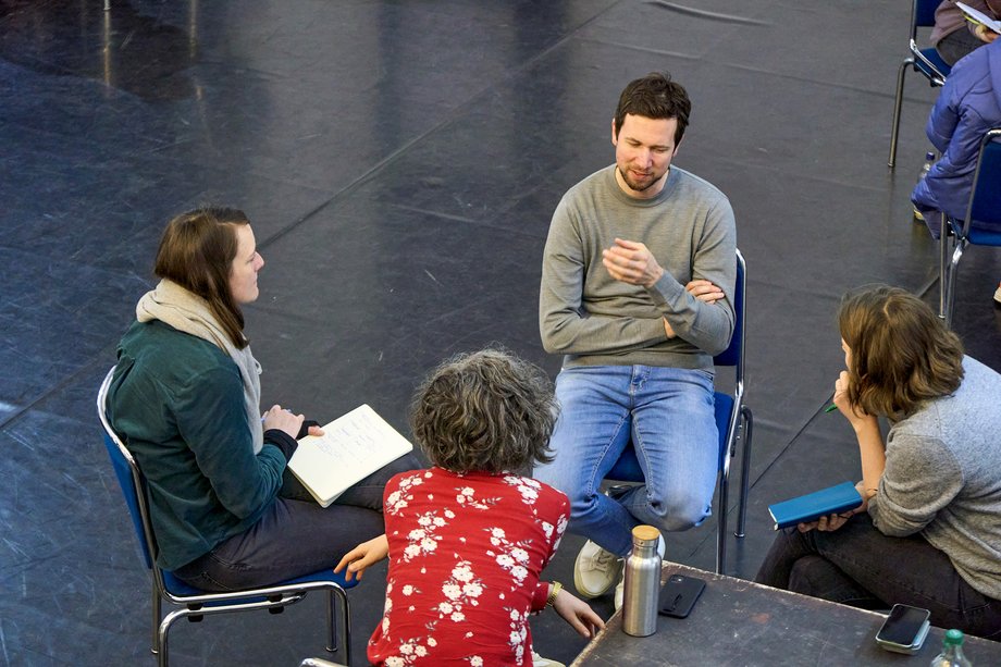 Vier Studierende sitzen im Kreis auf Stühlen und unterhalten sich