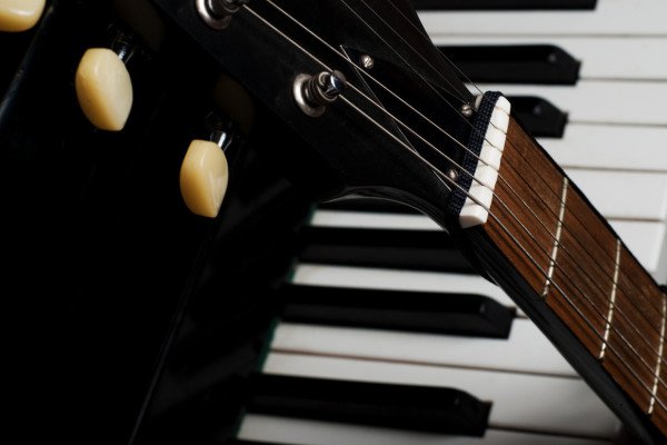 Nahaufnahme von einer Gitarre, die an einem Klavier lehnt