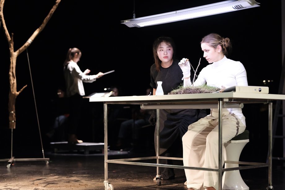 2 women at a table with neon lamp and various research utensils