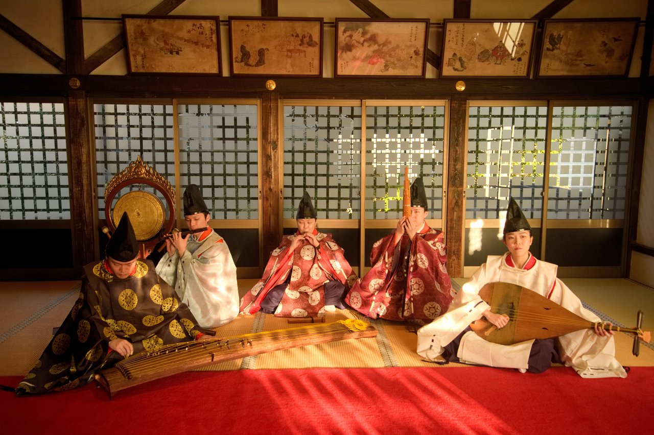 Gruppe traditionell japanisch gekleideter Personen in einem Raum sitzend