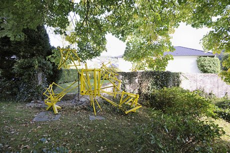 abstract sculpture made of yellow rods in a park