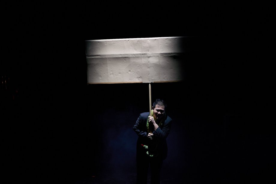 Man on dark stage with empty sign