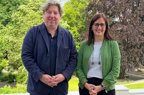 Porträtfoto von einer Frau und einem Mann vor einem landschaftlichen Hintergrund