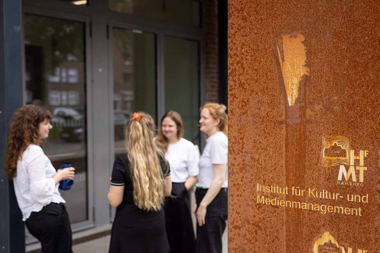 Vier Studierende vor dem Eingangsportal zum KMM