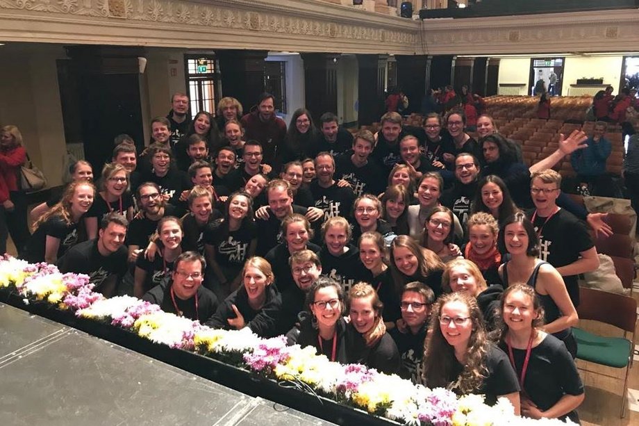 Lots of smiling people looking into the camera at the edge of a concert stage