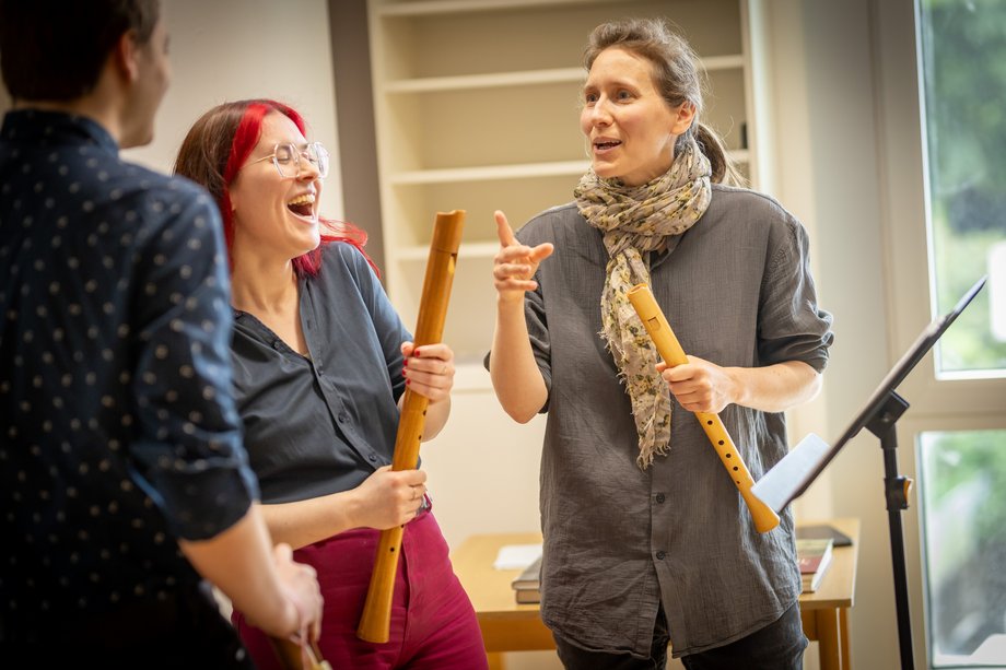 3 people with recorders in their hands, laughing